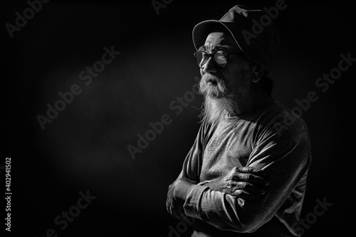 portrait on dark background of senior man standing with arm crossed