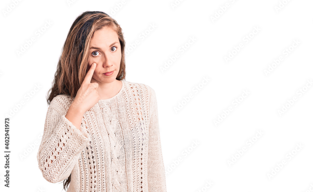 Young beautiful blonde woman wearing casual sweater pointing to the eye watching you gesture, suspicious expression Young beautiful blonde woman wearing casual sweater pointing to the eye watching you gesture, suspicious expression
