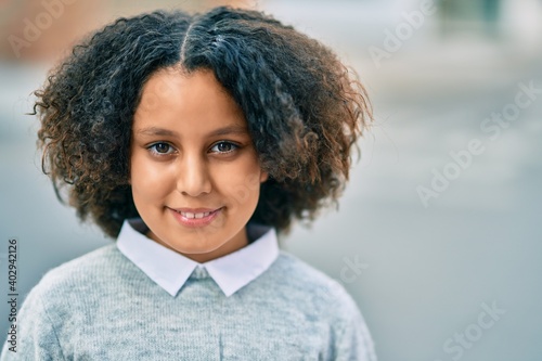 Adorable hispanic child girl smiling happy standing at the city.