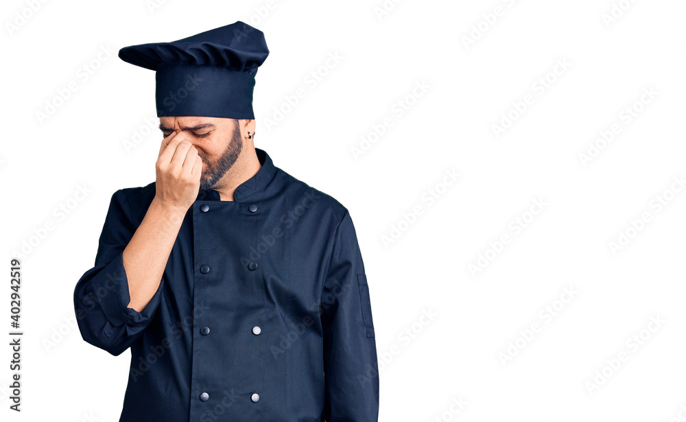 Young hispanic man wearing cooker uniform tired rubbing nose and eyes feeling fatigue and headache. stress and frustration concept. Young hispanic man wearing cooker uniform tired rubbing nose and eyes feeling fatigue and headache. stress and frustration concept.