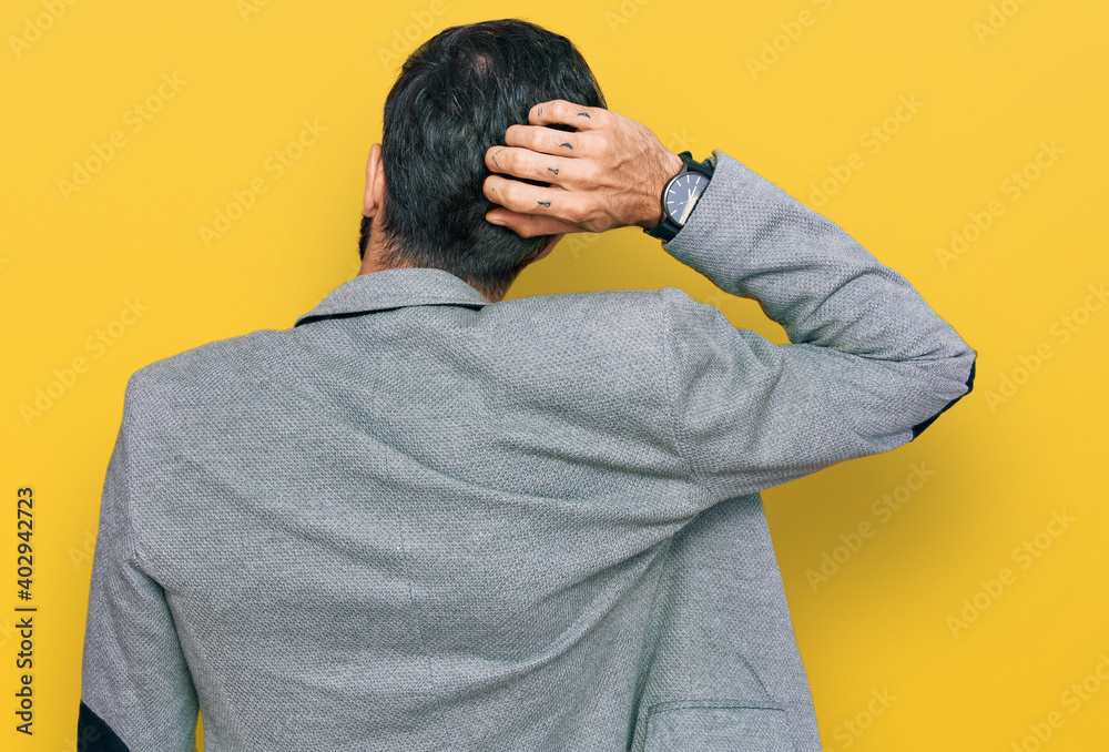 Young hispanic man wearing business clothes backwards thinking about doubt with hand on head Young hispanic man wearing business clothes backwards thinking about doubt with hand on head