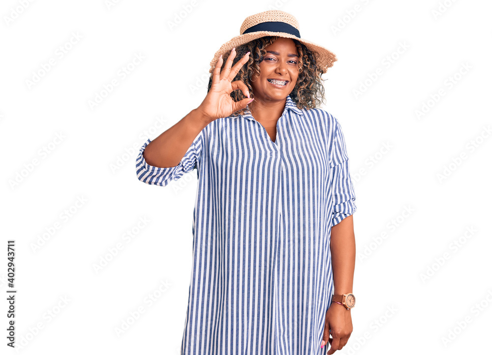 Young african american plus size woman wearing summer hat smiling positive doing ok sign with hand and fingers. successful expression. Young african american plus size woman wearing summer hat smiling positive doing ok sign with hand and fingers. successful expression.