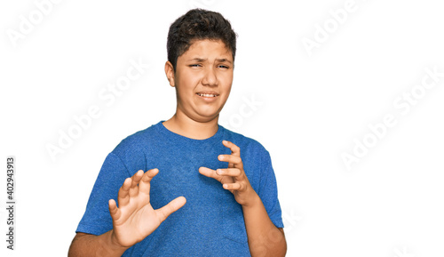 Teenager hispanic boy wearing casual clothes disgusted expression, displeased and fearful doing disgust face because aversion reaction. with hands raised