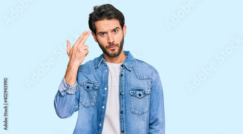 Canvas Print Young hispanic man wearing casual clothes shooting and killing oneself pointing hand and fingers to head like gun, suicide gesture