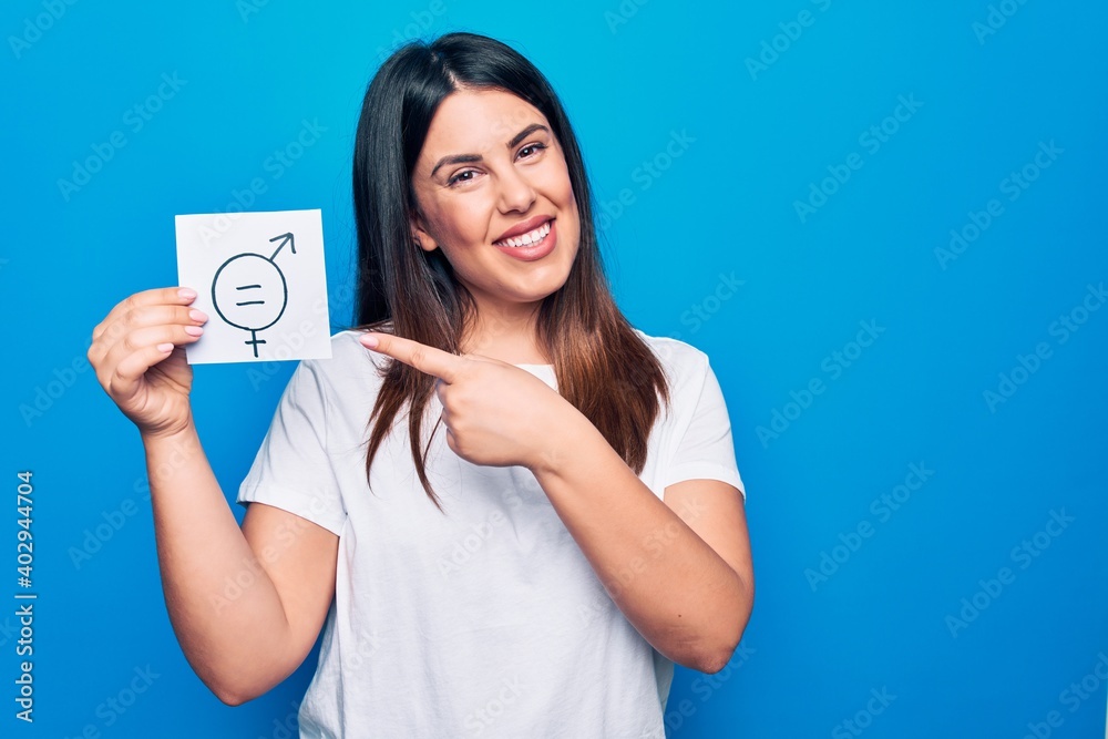 Young beautiful woman asking for sex discrimination holding paper with gender equality concept smiling happy pointing with hand and finger Young beautiful woman asking for sex discrimination holding paper with gender equality concept smiling happy pointing with hand and finger