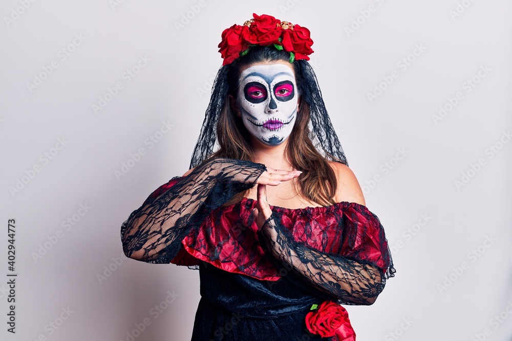 Young woman wearing day of the dead costume over white doing time out gesture with hands, frustrated and serious face