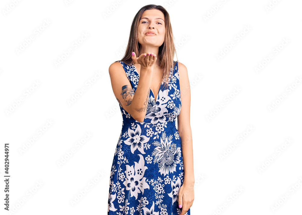 Beautiful caucasian woman wearing summer dress looking at the camera blowing a kiss with hand on air being lovely and sexy. love expression. Beautiful caucasian woman wearing summer dress looking at the camera blowing a kiss with hand on air being lovely and sexy. love expression.