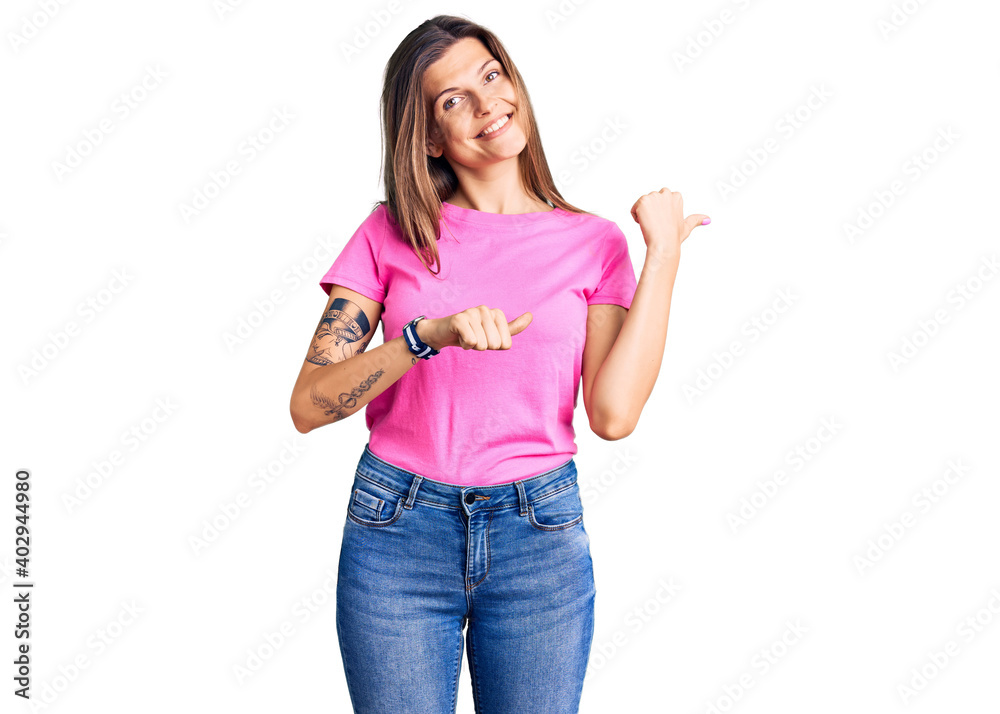 Beautiful caucasian woman wearing casual clothes pointing to the back behind with hand and thumbs up, smiling confident