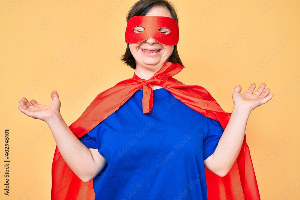 Brunette woman with down syndrome wearing super hero costume celebrating mad and crazy for success with arms raised and closed eyes screaming excited. winner concept Brunette woman with down syndrome wearing super hero costume celebrating mad and crazy for success with arms raised and closed eyes screaming excited. winner concept