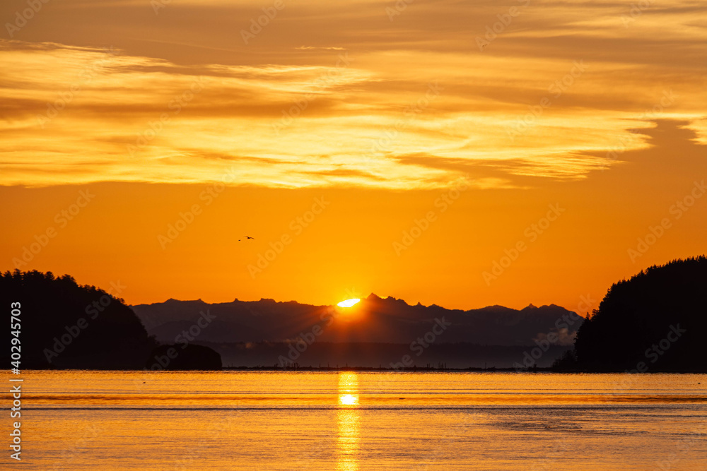 Dramatic sun rising between two hills with water in the foreground. Dramatic sun rising between two hills with water in the foreground.