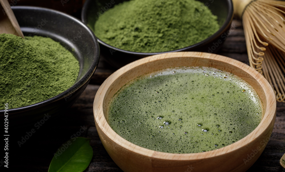 Japanese organic matcha green tea powder in bowl with wire whisk and green tea leaf on wooden background, Organic product from the nature for healthy with traditional style