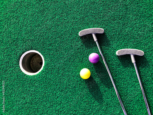 Mini golf clubs and balls on putting green artificial grass carpet