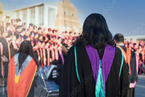 Rear view of the university graduates line up for degree award in university graduation ceremony. The university graduates are gathering in the university graduation ceremony. Crowd of the graduates.