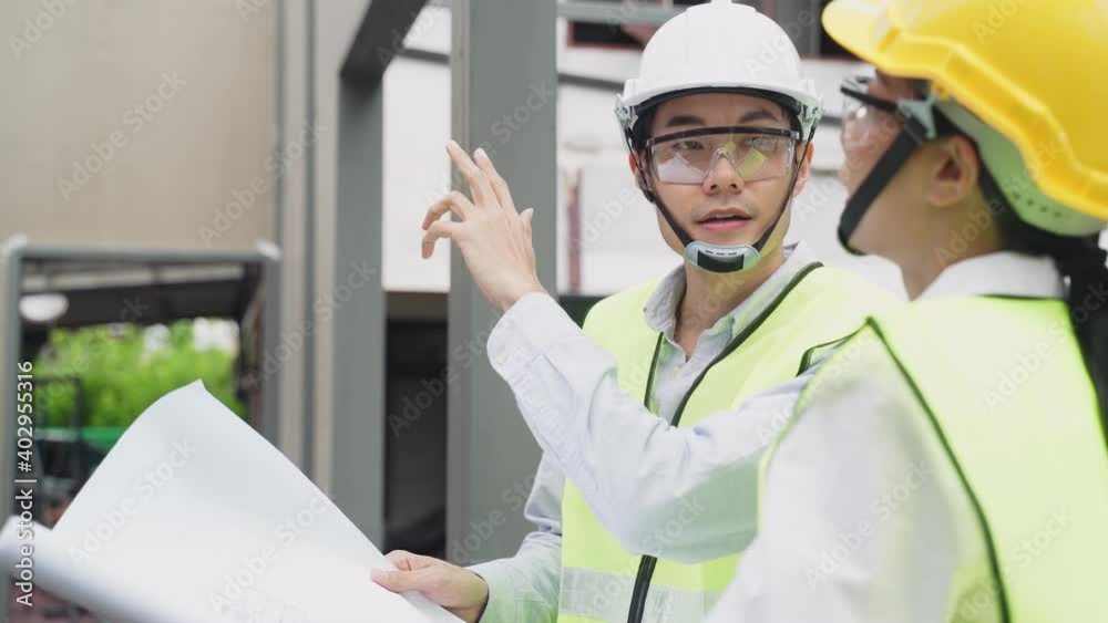 Asian young engineer man explaining job on drawing to female worker. Asian young engineer man explaining job on drawing to female worker.