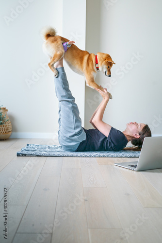 Doga or Doga yoga is the practice of yoga as exercise with dogs. Online yoga at home. Young woman and her dog training together