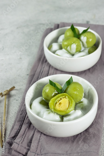 Putri mandi or badak berendam, Steamed glutinous rice with potato balls filled with green bean paste and serve with coconut milk. Selective focus photo