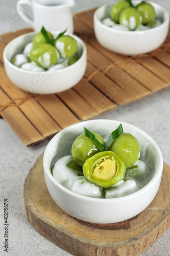 Putri mandi or badak berendam, Steamed glutinous rice with potato balls filled with green bean paste and serve with coconut milk. Selective focus