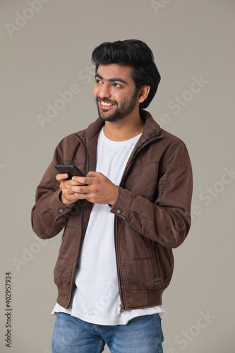 A YOUNG MAN LOOKING ABOVE WHILE USING MOBILE PHONE	 photo