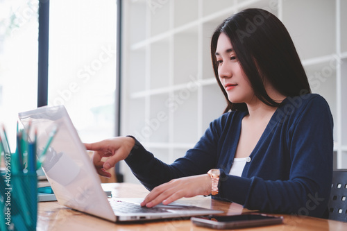 Attractive young asian freelancer business woman working with computer laptop in co-working space or coffee shop.