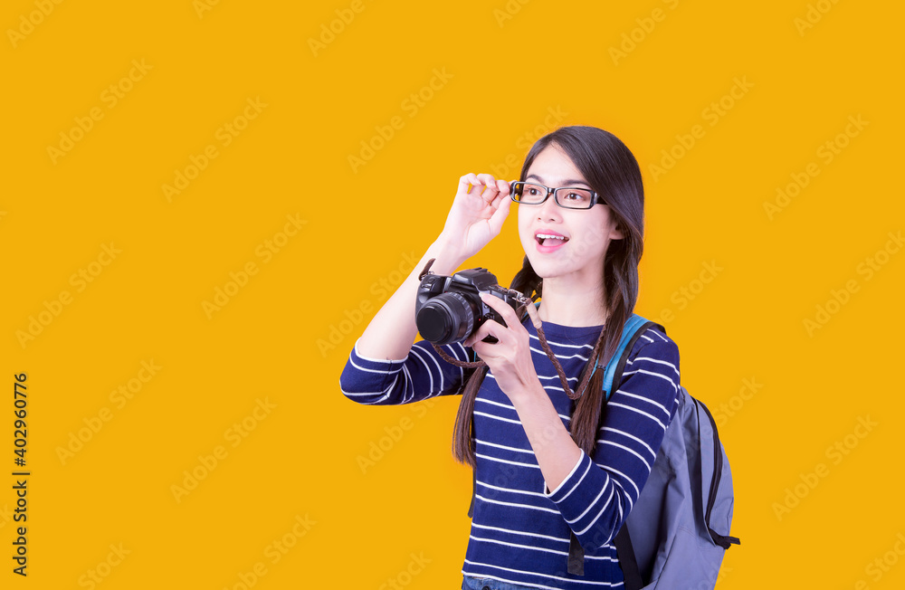 Asian woman tourist was running her to various places.happy excited emotional young woman photographer tourist standing isolated over Orange background Asian woman tourist was running her to various places.happy excited emotional young woman photographer tourist standing isolated over Orange background