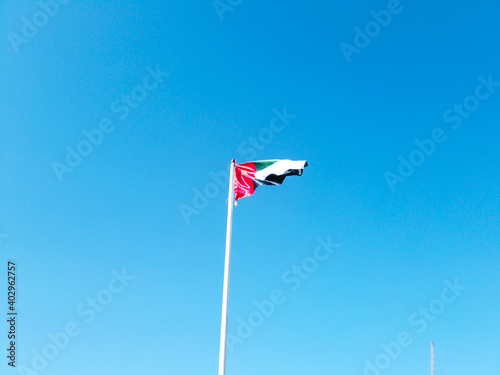 The United Arab Emirates flag waving against the beautiful blue sky on a sunny day