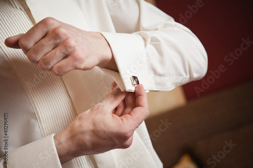 Groom's morning. Wedding preparing. Man in white shirt putting on cufflinks. Business dress code