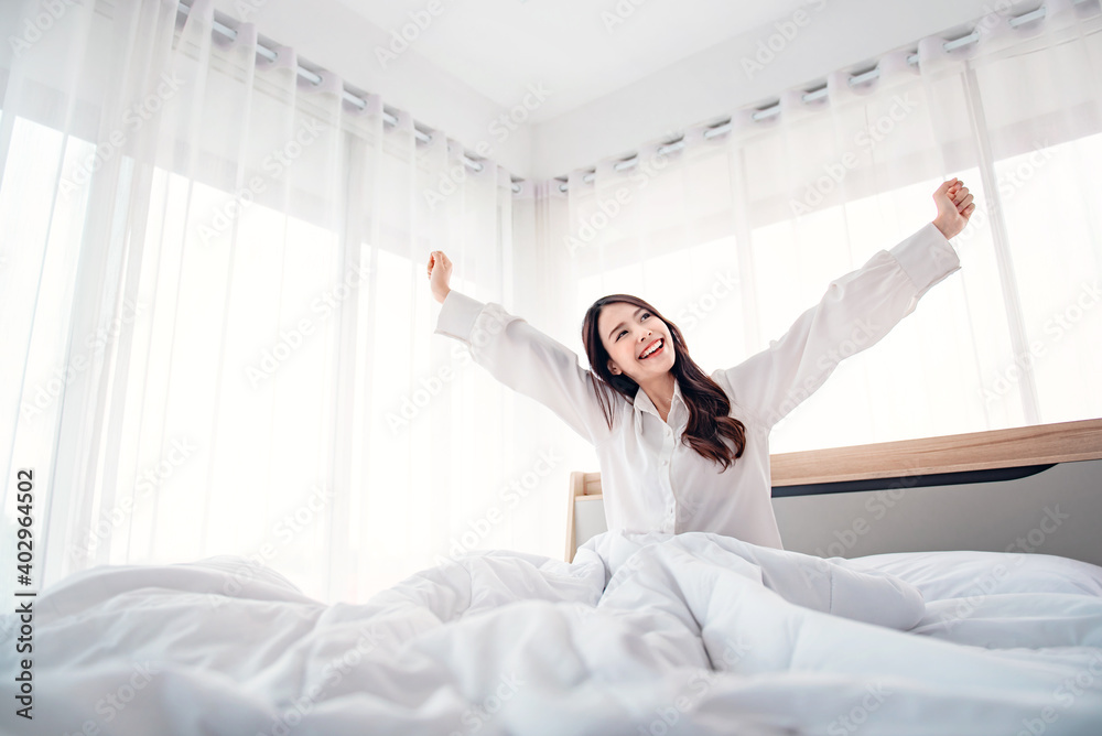 Happy asian woman stretching hands in bed after wake up in the morning, Concept of a new day and joyful weekend. Happy asian woman stretching hands in bed after wake up in the morning, Concept of a new day and joyful weekend.