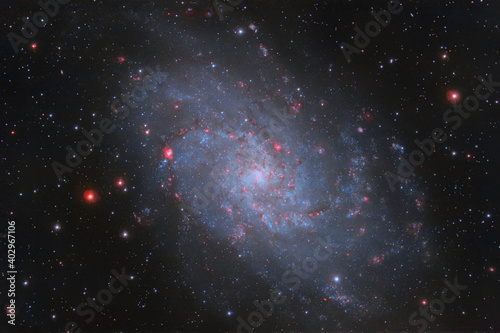 Galaxy m33 against the background of dark space and multi-colored stars. Photo of a real space object, photographed through a telescope.