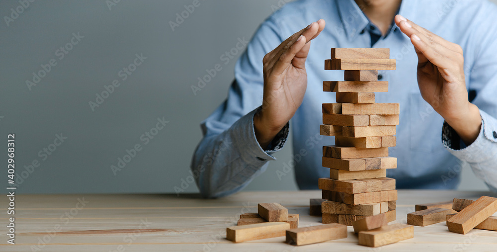 Planning, risk and strategy in business, businessman placing wooden block on a tower. Planning, risk and strategy in business, businessman placing wooden block on a tower.