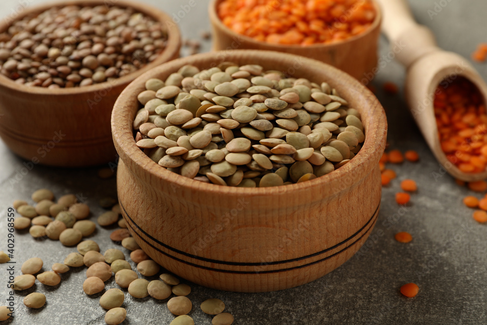 Scoop and bowls with different legumes on gray background Scoop and bowls with different legumes on gray background