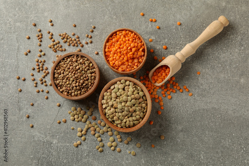 Scoop and bowls with different legumes on gray background