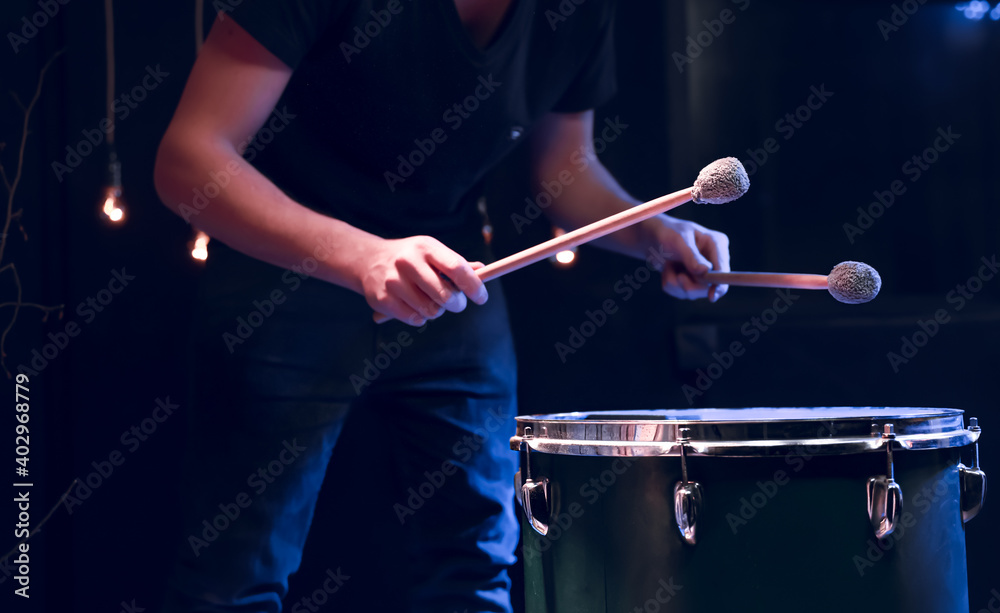 The drummer plays with mallets on floor tom in dark room. The drummer plays with mallets on floor tom in dark room.