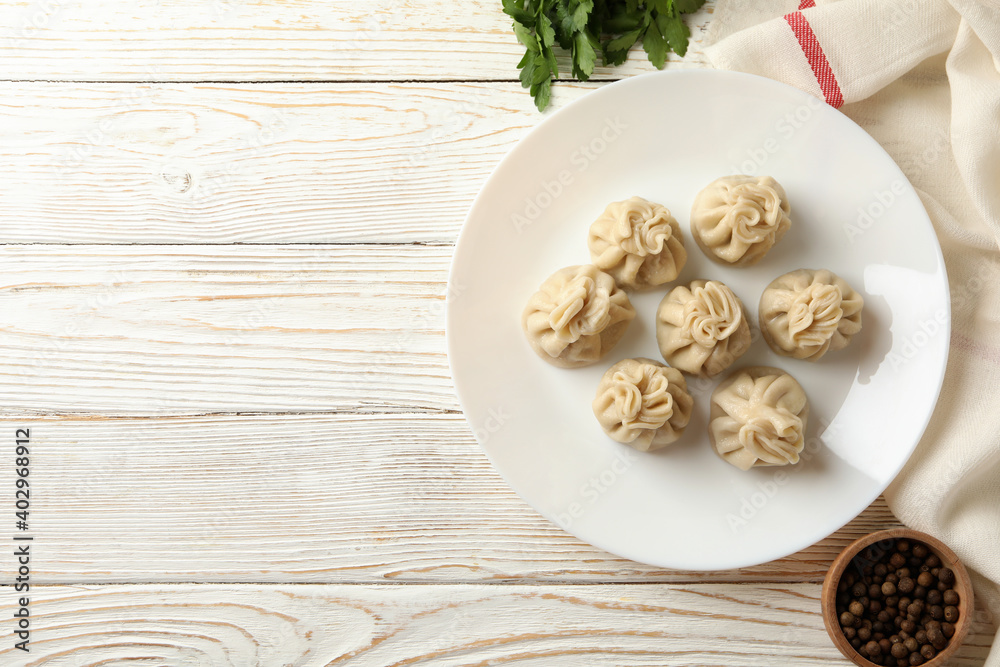 Concept of tasty lunch with plate of khinkali on white wooden background Concept of tasty lunch with plate of khinkali on white wooden background