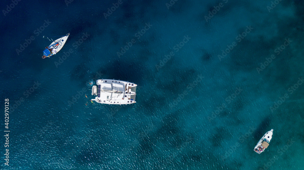 Catamaran sailing in blue, turquoise water in Greece, beautiful catamaran next to the coast during summer holiday, view from drone Catamaran sailing in blue, turquoise water in Greece, beautiful catamaran next to the coast during summer holiday, view from drone