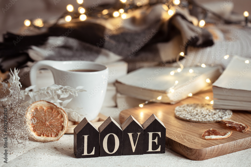 Cozy home composition with decorative word love on blurred background with bokeh.