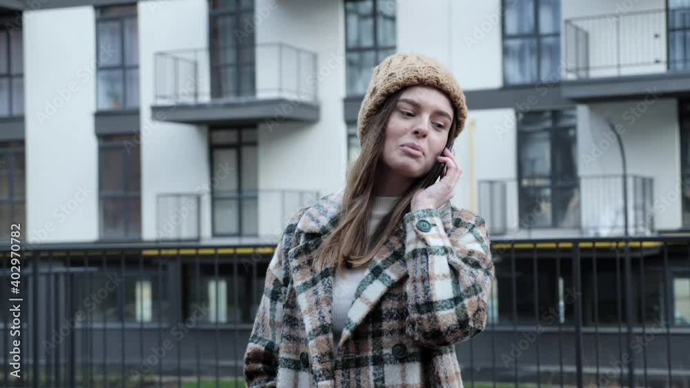 Cute and pretty girl with a beautiful appearance and stylish clothes talking on the phone with friends on the urban street background of new city building. Cute and pretty girl with a beautiful appearance and stylish clothes talking on the phone with friends on the urban street background of new city building.
