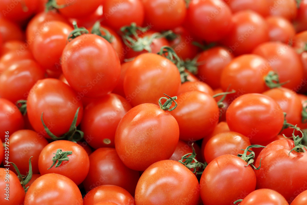 Red cherry tomatoes with green cut, fresh vegetables on the market