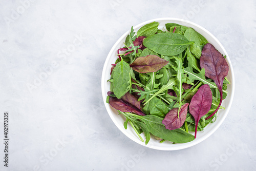 Healthy salad, leaves mix salad of spinach, arugula, lettuce in white plate on grey table .