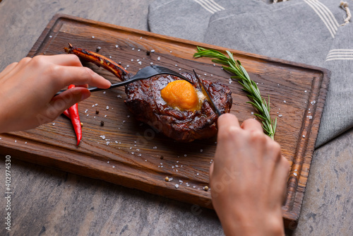 Barbecue tomahawk steak with spices served on a rustic wooden board over wooden background. photo