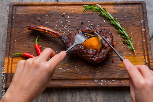 Barbecue tomahawk steak with spices served on a rustic wooden board over wooden background. photo