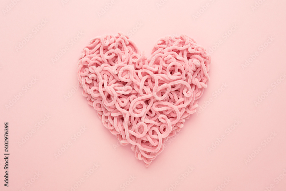 Valentines Day Heart made of yarn on pink background. Copy space, Flat lay. Compound love symbol.