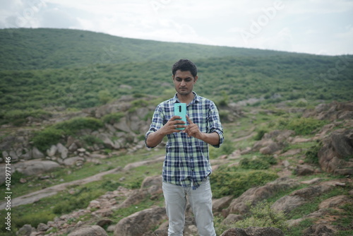 dausa, Rajasthan, India - august 15 , 2020 Happy male using smartphone at mountains, he chatting Online Messaging on mobile.