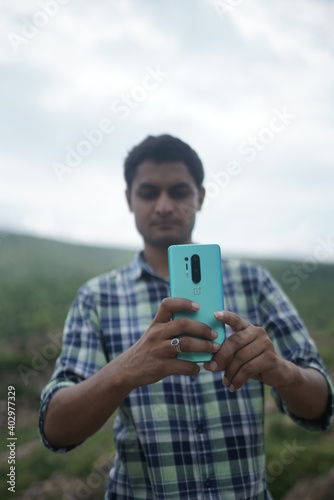 dausa, Rajasthan, India - august 15 , 2020 Happy male using smartphone at mountains, he chatting Online Messaging on mobile.