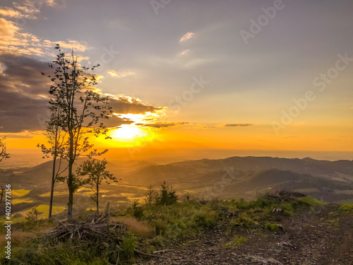 A view of a landscape full of mountains during a golden sunset with the sun on the horizon and a view of the sun from the top of Mount Ondrejnik. photo