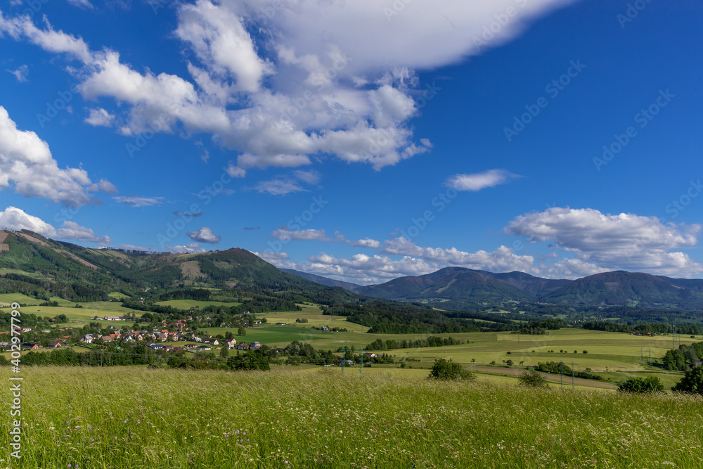 Under the sun and shadows Ondřejník and a view of other Beskydy hills and mountains with white clouds and blue sky in the background. Under the sun and shadows Ondřejník and a view of other Beskydy hills and mountains with white clouds and blue sky in the background.
