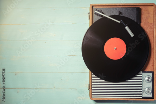 Vintage gramophone with a vinyl record on rustic wooden table, top view and copy space.