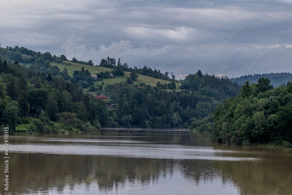 Water level of the Bystricka reservoir during a rainy afternoon with dark clouds in the sky.