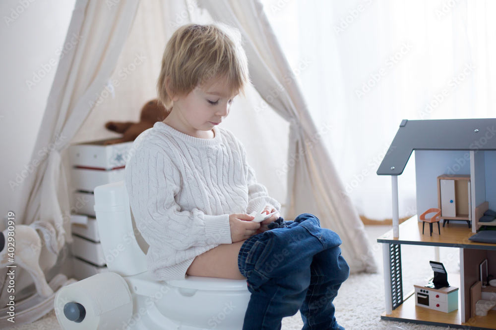 Cute toddler child, boy, sitting on a baby toilet potty, playing Cute toddler child, boy, sitting on a baby toilet potty, playing
