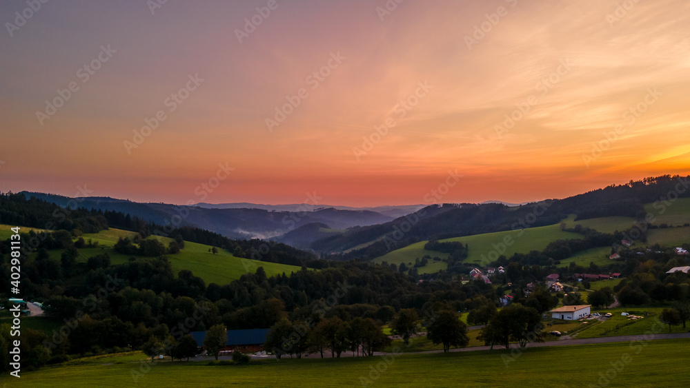 Fototapeta premium Aerial view of a hill on the Bystricka dam and the surrounding hills during sunset between the valley appears fog.