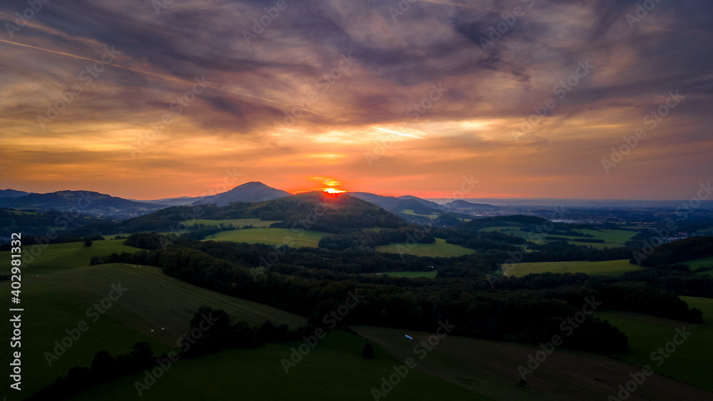 Aerial view of colorful clouds and Ondrejnik peak lying on the horizon during sunset.